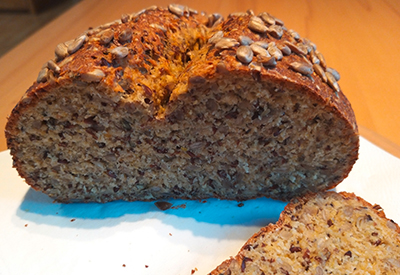 ein aufgeschnittener Laib Sonnenblumenbrot mit einer liegenden Schnitte